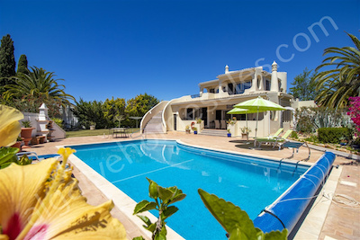 View across a pool to a villa and gardens