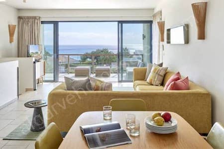 Looking across the living room through open terrace doors to the view of trees and ocean