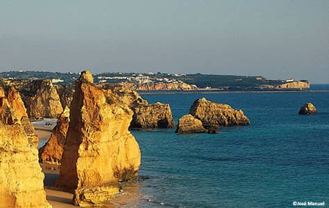 Praia da rocha beach, rocks with Pintadinha promotory in the distance acrosse the sea