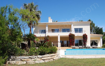 view of a villa across gardens and infinity pool