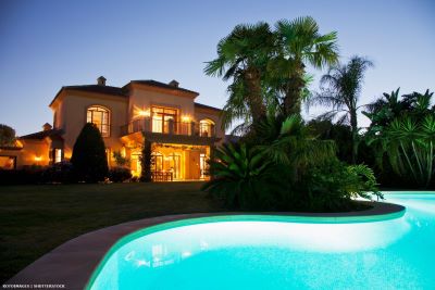 Lit villa with pool at dusk