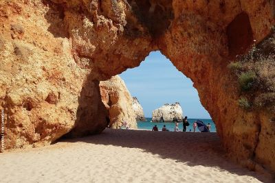 View through sandstone arch to vamily on the beach and the ocean behind them