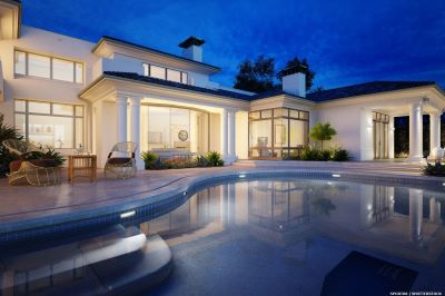 Villa at dusk with lights on and pool