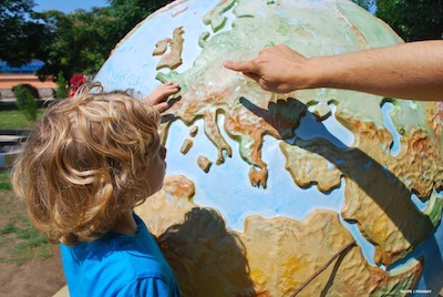 Child and adult looking at a globe out of doors