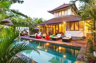 Ville viewed across patio and swimming pool with garden bordering